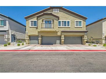 Three-story townhome with beige exterior and individual garages under each unit at 4720 Flower Moon Ave # 101, North Las Vegas, NV 89084