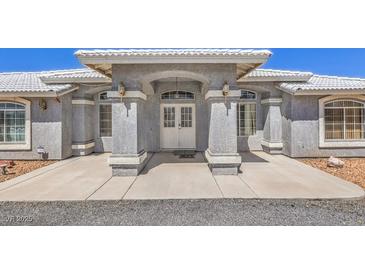 Inviting front entrance features a covered porch with decorative pillars and a double door entry for a grand arrival at 1410 Tiptop Trl, Pahrump, NV 89048