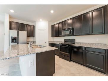 Modern kitchen features dark cabinets, stainless steel appliances, and a large island with granite countertops at 2824 Mozia Ct, Henderson, NV 89044