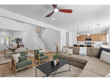 Bright living room featuring modern furnishings, hardwood floors, and an open floor plan leading to the kitchen and dining area at 9115 Weeping Hollow Ave, Las Vegas, NV 89178
