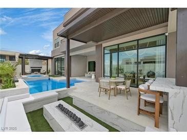 Beautiful backyard oasis featuring a modern pool, a cozy fire pit, and an outdoor dining area perfect for entertaining at 10718 Desert Heights Ave, Las Vegas, NV 89135