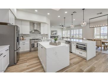 Modern white kitchen featuring stainless steel appliances, center islands, and wood-look flooring at 1964 Oliver Springs St, Henderson, NV 89052
