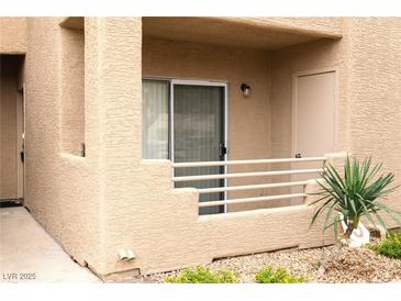 Exterior view of a condo with a private patio, tan stucco walls, and a small potted plant at 2191 Bay Club Dr # 102, Laughlin, NV 89029