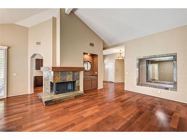 Spacious living room featuring a cozy fireplace, high ceilings, and rich hardwood flooring at 2832 Cape Hope Way, Las Vegas, NV 89121