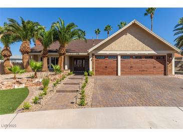 Beautiful single-story home boasts a three-car garage, brick driveway, and lush landscaping with mature palm trees at 326 Fuente Dr, Henderson, NV 89014