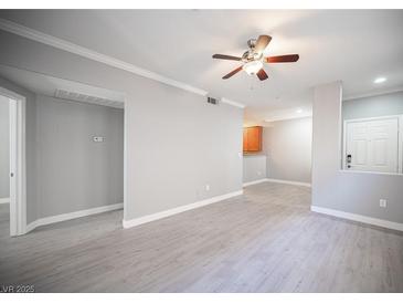 A spacious living room featuring modern gray wood flooring and a ceiling fan for comfortable living at 4400 S Jones Blvd # 2075, Las Vegas, NV 89103
