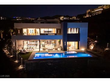 Stunning modern home exterior with a sparkling pool and outdoor entertaining space at night at 609 Sleeping Dragon Dr, Henderson, NV 89012