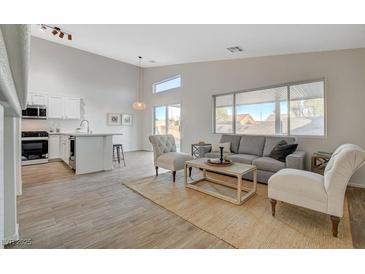 Bright living room featuring neutral tones, wood-look flooring, and an open concept design flowing into the kitchen at 4331 Golden Palomino Ln, North Las Vegas, NV 89032