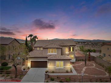 Charming two-story home with stone accents and a well-manicured front yard at dusk at 7756 River Mist Ct, Las Vegas, NV 89113