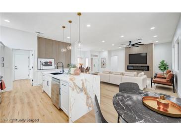 Bright, open-concept living space featuring a modern kitchen with a marble island and a comfortable seating area at 2353 Lauren Dr, Las Vegas, NV 89134