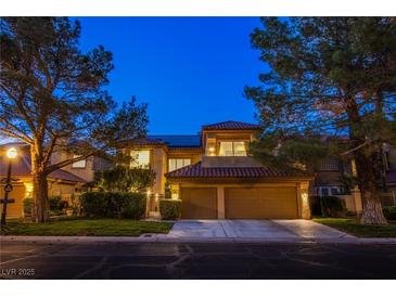 Inviting two-story home featuring a well-manicured lawn, mature trees and a convenient two-car garage at 7940 Castle Pines Ave, Las Vegas, NV 89113