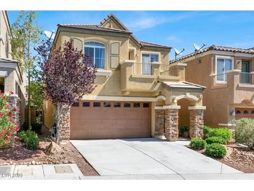 Two-story home featuring a two-car garage, stone accents, balcony, and landscaped front yard at 10230 Danskin Dr, Las Vegas, NV 89166