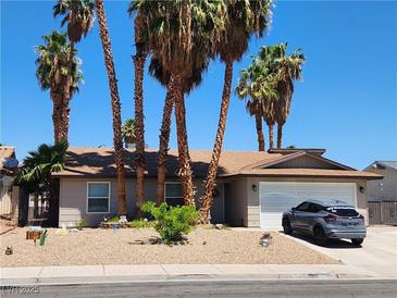 Charming single-story home featuring desert landscaping, a two-car garage, and mature palm trees at 3143 La Mesa Dr, Henderson, NV 89014