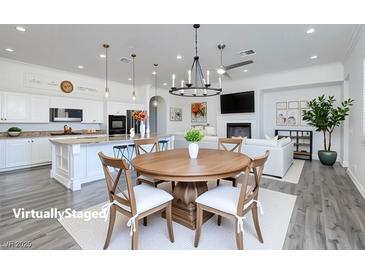 Bright open-concept living room with a modern kitchen, dining area, and fireplace at 472 Via Stretto Ave, Henderson, NV 89011