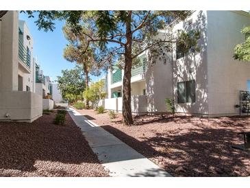 View of modern townhouse exteriors with neat landscaping and walkways under a clear blue sky at 7100 Pirates Cove Rd # 2065, Las Vegas, NV 89145