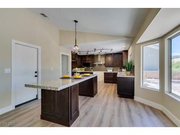 Modern kitchen features an island, wood cabinets, granite countertops, and stainless steel appliances at 9800 Rosamond Dr, Las Vegas, NV 89134