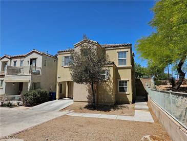 Two-story home featuring tan stucco and a concrete driveway with a young tree in front at 7461 Enviable Ct, Las Vegas, NV 89149