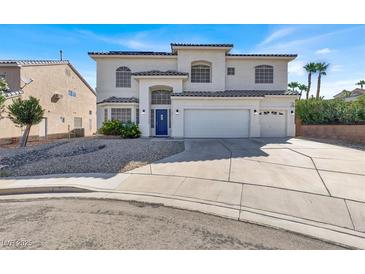Inviting stucco two-story home with a three-car garage and a blue front door at 7492 Midfield Ct, Las Vegas, NV 89120