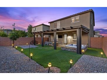 A backyard with pavers, grass, spa, pergola, and bistro lights is great for entertaining guests at 8013 Green River Knob St, Las Vegas, NV 89113
