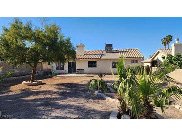 View of the spacious backyard featuring desert landscaping, a mature tree, and a patio area at 4285 El Como Way, Las Vegas, NV 89121