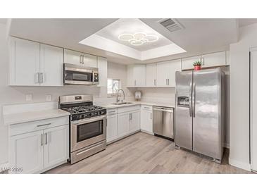 Bright kitchen featuring stainless steel appliances, white cabinetry, and a stylish light fixture at 4745 Madrigal Way, Las Vegas, NV 89122