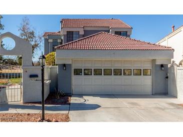 View of the garage and entry gate of this well maintained home featuring a terracotta roof and neutral stucco exterior at 5221 Crooked River Cir, Las Vegas, NV 89149