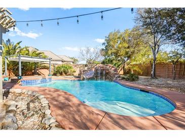 Beautiful pool with rock waterfall feature, lush landscaping, and spa for outdoor relaxation at 6907 May Basket Ave, Las Vegas, NV 89131