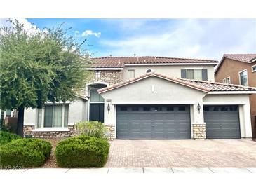 Two-story home featuring a tile roof, three-car garage, and manicured landscaping in a suburban neighborhood at 7020 Puetollano Dr, North Las Vegas, NV 89084