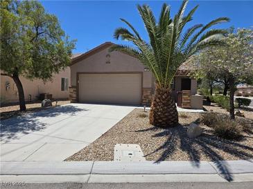 Charming single-story home featuring a two-car garage, desert landscaping, and a large palm tree at 7957 Fantail Dr, North Las Vegas, NV 89084