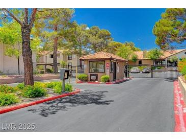 View of the community entrance gate with mature trees and manicured landscaping offering security and curb appeal at 2451 N Rainbow Blvd # 1066, Las Vegas, NV 89108