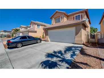 Inviting two-story home with a tile roof, attached garage, and a neatly maintained front yard with a long driveway at 8370 Lost Lake Ct, Las Vegas, NV 89147