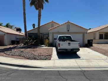 Single story home with white truck in driveway, palm trees, and low maintenance landscaping at 1409 Velvet Leaf Dr, North Las Vegas, NV 89032
