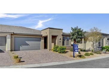 Charming single-story home with a neutral color scheme, desert landscaping, and a brick driveway at 9903 Spinel Pl, Las Vegas, NV 89143