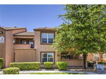 Two-story condo featuring desert landscaping with a mix of green bushes and a tall tree at 1150 N Buffalo Dr # 1022, Las Vegas, NV 89128