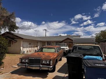 House exterior featuring a driveway with multiple cars parked in front and some trash bins at 212 Hinkle St, Las Vegas, NV 89107