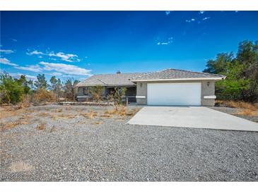 Charming single-story home with a two-car garage and a desert landscape, bathed in bright sunlight at 1351 Fawn St, Pahrump, NV 89048