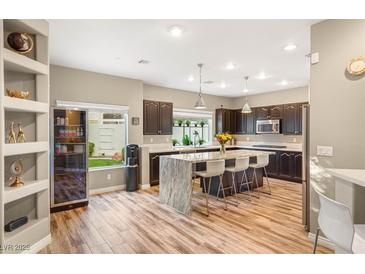 Bright kitchen features wooden floors, stainless steel appliances, large marble island, and recessed lighting at 8100 Lake Hills Dr, Las Vegas, NV 89128