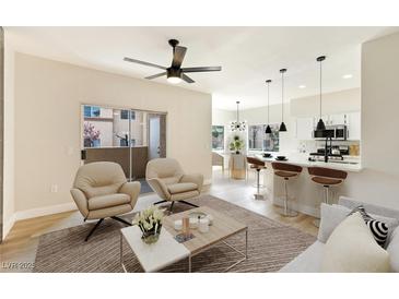 Bright living room featuring wood floors, modern ceiling fan, and open concept to the kitchen at 8501 W University Ave # 1042, Las Vegas, NV 89147