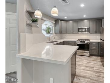 Modern kitchen features quartz countertops, stainless steel appliances, gray cabinets, and stylish pendant lighting at 5018 S Rainbow Blvd # 202, Las Vegas, NV 89118