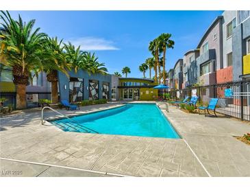 Community pool with lounge chairs and palm trees under a bright blue sky at 9050 W Tropicana Ave # 1075, Las Vegas, NV 89147