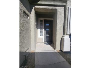 Inviting front entrance with a textured stucco facade and decorative glass block window at 10548 Ettenmoor Ave, Las Vegas, NV 89135