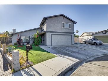 Two-story house featuring a gray exterior, attached garage, and well-maintained front yard with green grass at 4474 Dawley Ct, Las Vegas, NV 89104