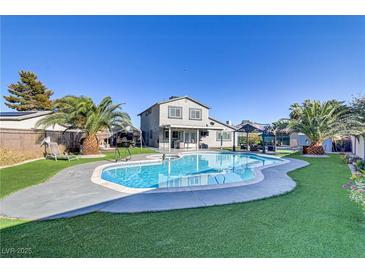 Inviting backyard with a large pool, lush green lawn, mature trees, and covered patio, perfect for outdoor entertaining at 4474 Dawley Ct, Las Vegas, NV 89104