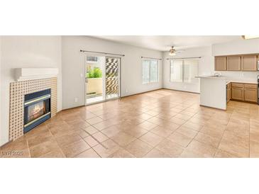 Bright living room boasts fireplace, neutral tile flooring and sliding door to patio at 4830 Grey Wolf Ln # 104, Las Vegas, NV 89149