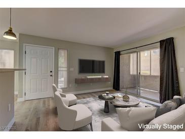 Bright living room with wood floors, neutral tones, a sliding glass door to the balcony, and contemporary furnishings at 5710 E Tropicana Ave # 1216, Las Vegas, NV 89122