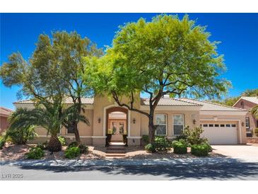 Charming single-story home featuring mature landscaping and a welcoming front entrance with a beautiful arched entryway at 10573 Bambola Pl, Las Vegas, NV 89135