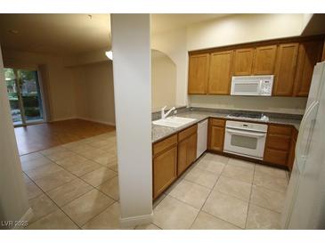 Well-lit kitchen with wooden cabinets, granite countertops, and tile flooring at 62 E Serene Ave # 129, Las Vegas, NV 89123