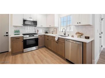 Bright kitchen features stainless steel appliances, two-tone cabinetry, and light countertops at 427 Wright Way, Henderson, NV 89015