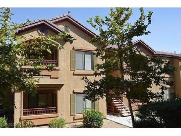 Two-story tan condo complex with greenery and stairs leading to the units at 8250 N Grand Canyon Dr # 2154, Las Vegas, NV 89166