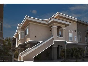Exterior view of a tan two-story condo with stairs outlined in white at 9330 W Maule Ave # 212, Las Vegas, NV 89148
